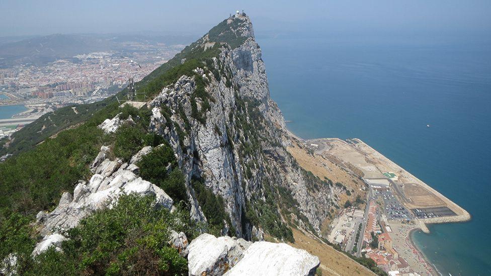 The Rock of Gibraltar juts out above the sea.