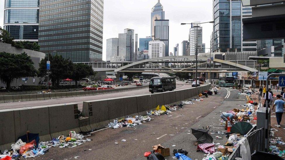 People walk on a street full of debris a day after a demonstration against a controversial extradition law proposal in Hong Kong