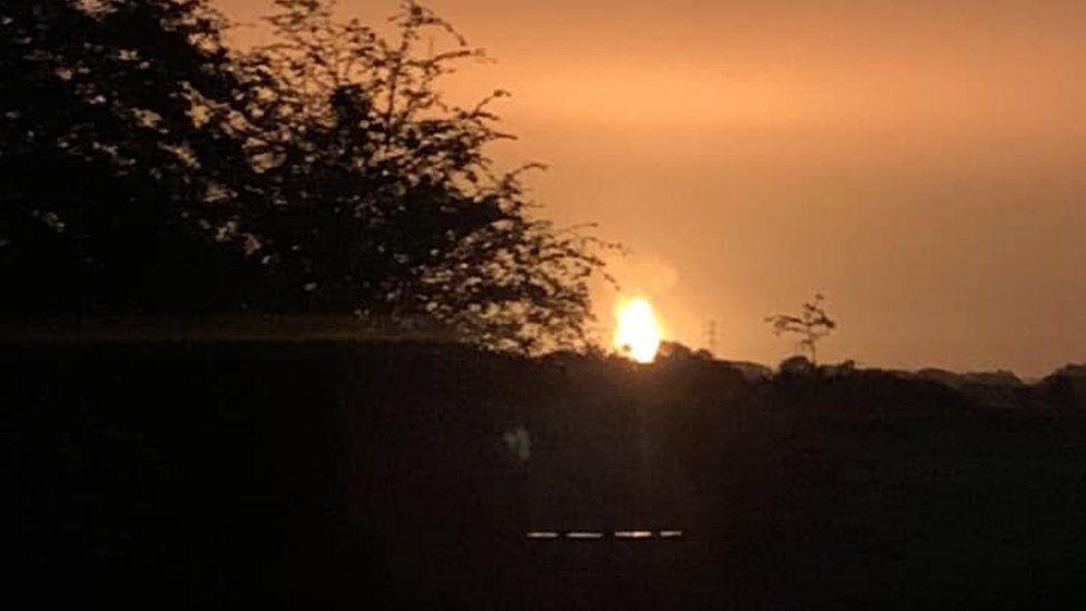 The fireball that light up the night sky after the explosion. The sky has an orange hue. Three branches could be seen as well.