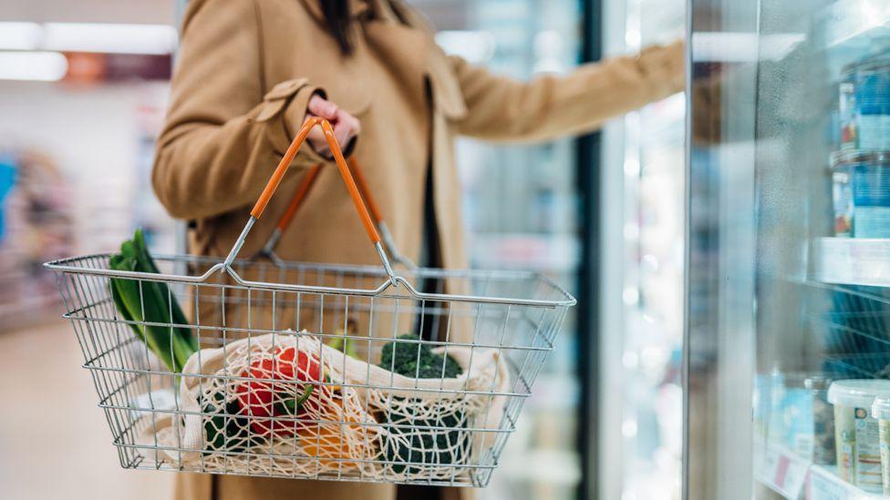 Shopper holding shopping basket in supermarket