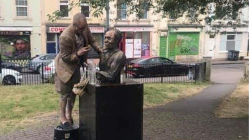 Image of man on a step stool by the statue