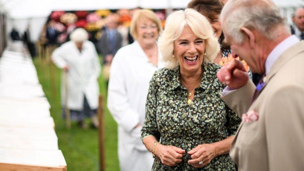 Kings Charles III and Queen Camilla laugh as they view a display during the Sandringham Flower Show at Sandringham House in Norfolk