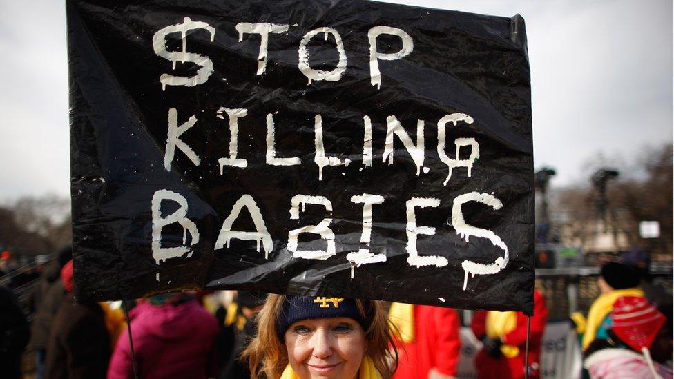 Protestor holding sign that says 'stop killing babies'