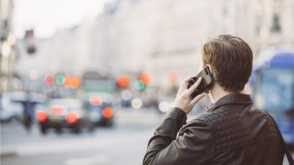 Man talking on the mobile phone on the street, rear view - stock photo