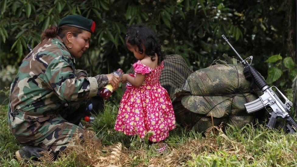 A Farc rebel pours juice for a local girl as she arrives at a transition zone in Cauca province in Colombia on 31 January 2017