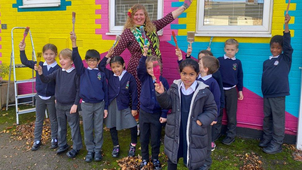 A group of school children standing with Tash Frootko and the newly painted mural