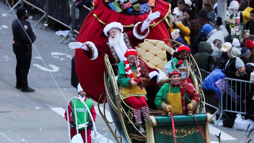 Father Christmas and a group of elves ride on a float through the Thanksgiving Parade