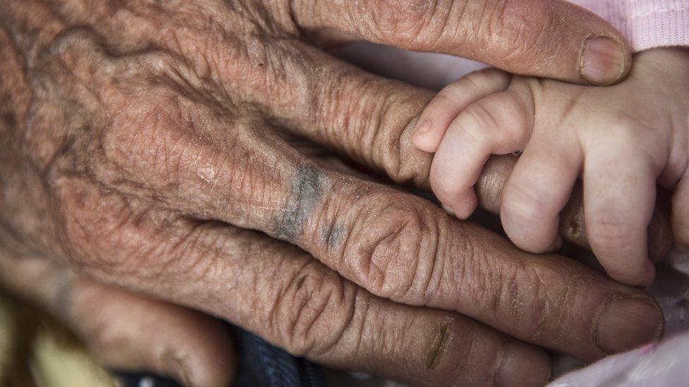 Baby's hand gripping grandmother's finger