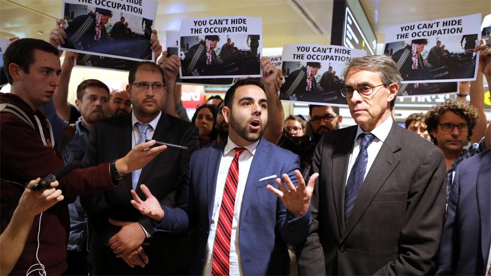 Omar Shakir (C), standing beside Kenneth Roth (R), speaks to reporters at Ben Gurion airport before leaving Israel (25 November 2019)