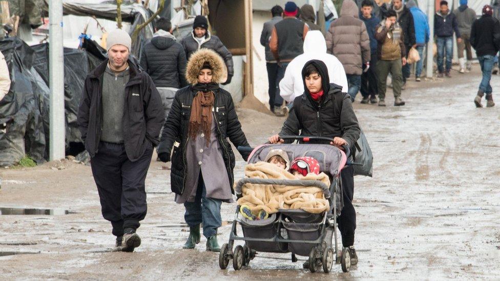 A woman pushes her children in a stroller on February 25, 2016 in the Jungle migrants and refugee camp in Calais, northern France.