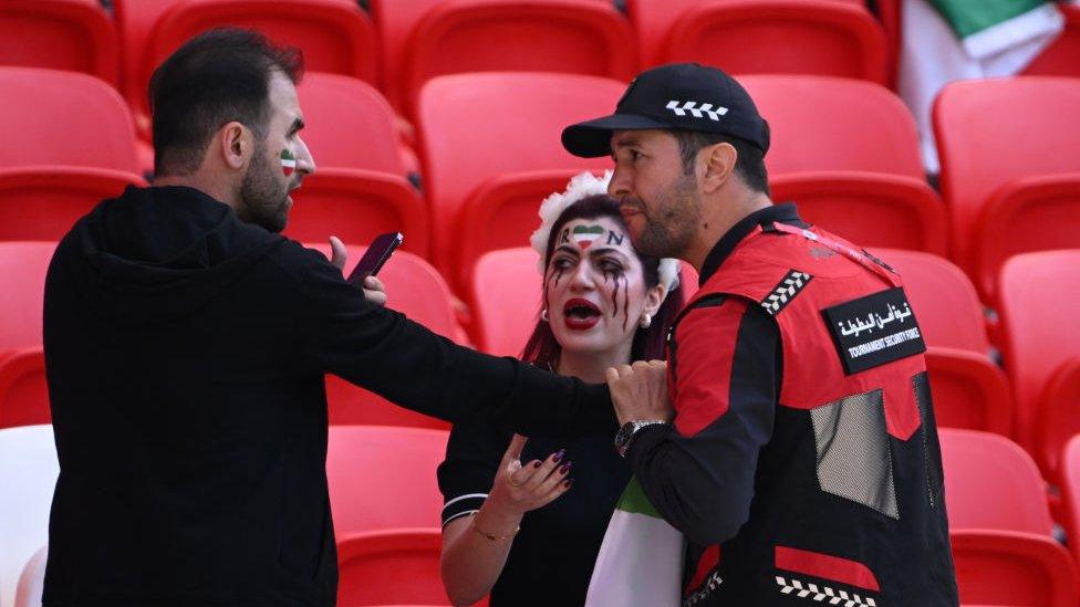 Security staff speak with fans holding up a shirt with the name of Mahsa Amini and a flag advocating for women's rights during the FIFA World Cup Qatar 2022 Group B match between Wales and IR Iran at Ahmad Bin Ali Stadium on November 25, 2022 in Doha, Qatar. People have continued demonstrating in Iran over the death of Mahsa Amini in September.