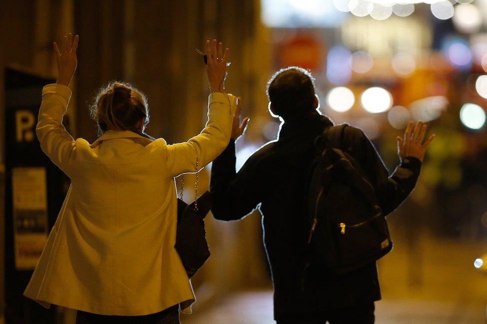 People raise their arms to show their hands as they walk towards police on a side road near the Champs Elysees Avenue in Paris, France, 20 April