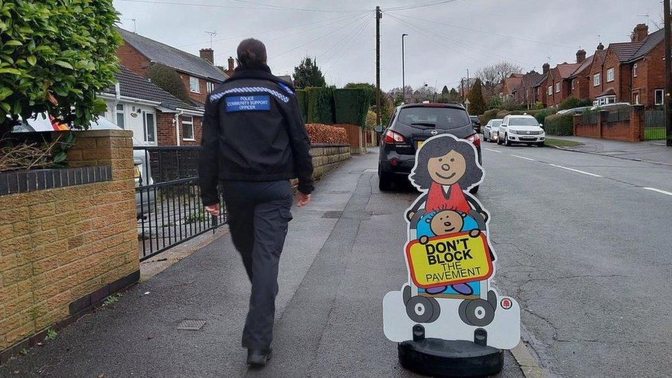 A police community support officer walks along a residential street while on a parking patrol