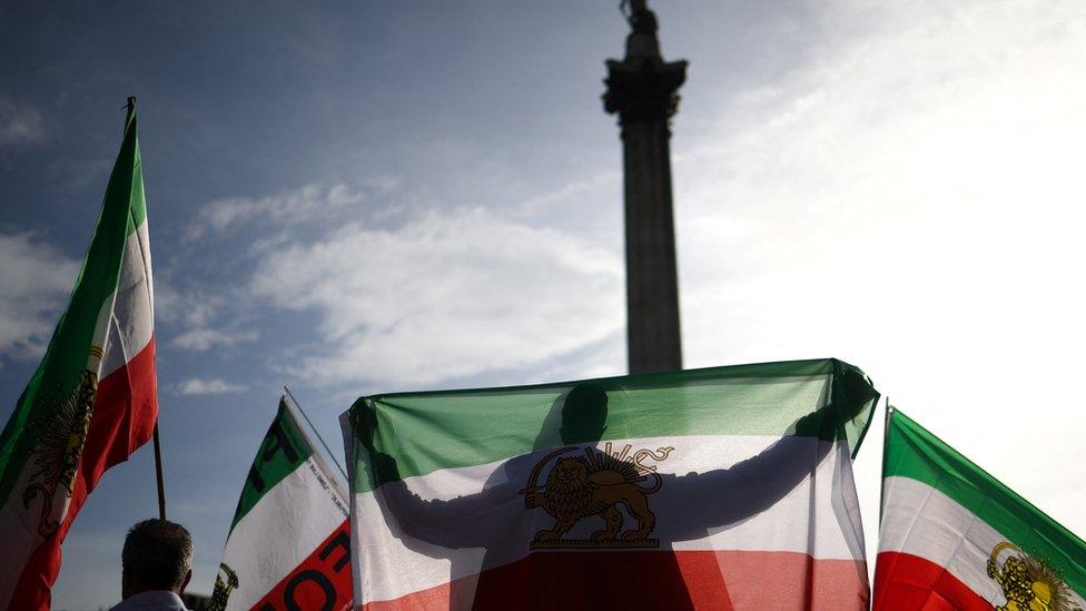 A man holds up a flag during the protest in London following the death of Mahsa Amini in Iran