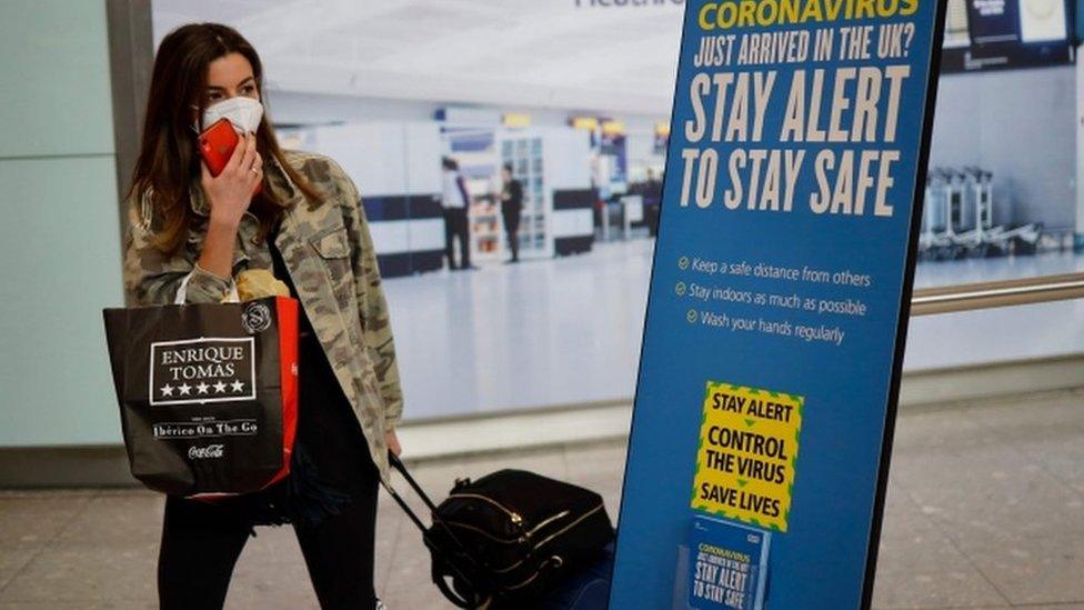 Woman wearing a face mask arrives at Heathrow airport