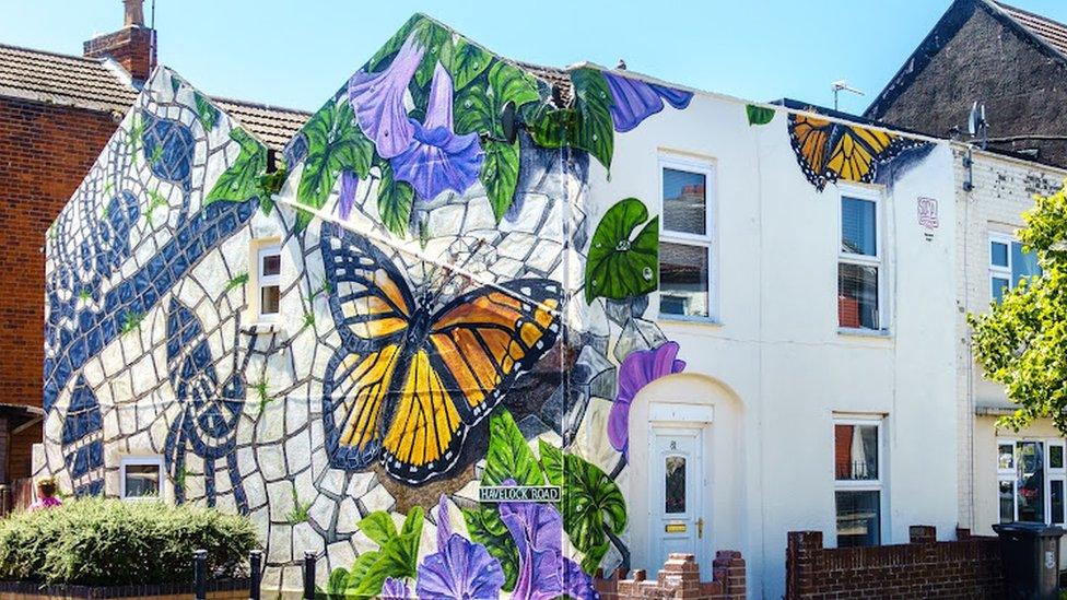 Butterfly street mural on the side of a house