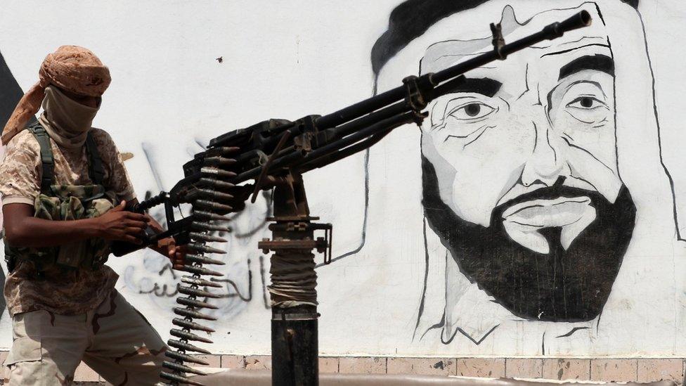 UAE-backed Yemeni pro-government fighter mans a machine-gun next to a mural in Mukalla showing the UAE's late founder and president, Sheikh Zayed bin Sultan Al Nahyan (8 August 2018)