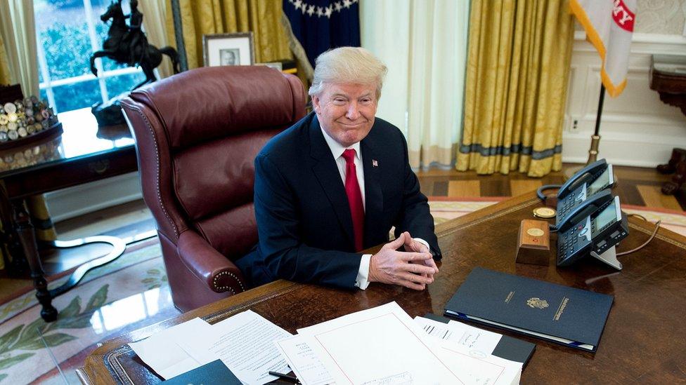 Donald Trump sits at his Oval Office desk.