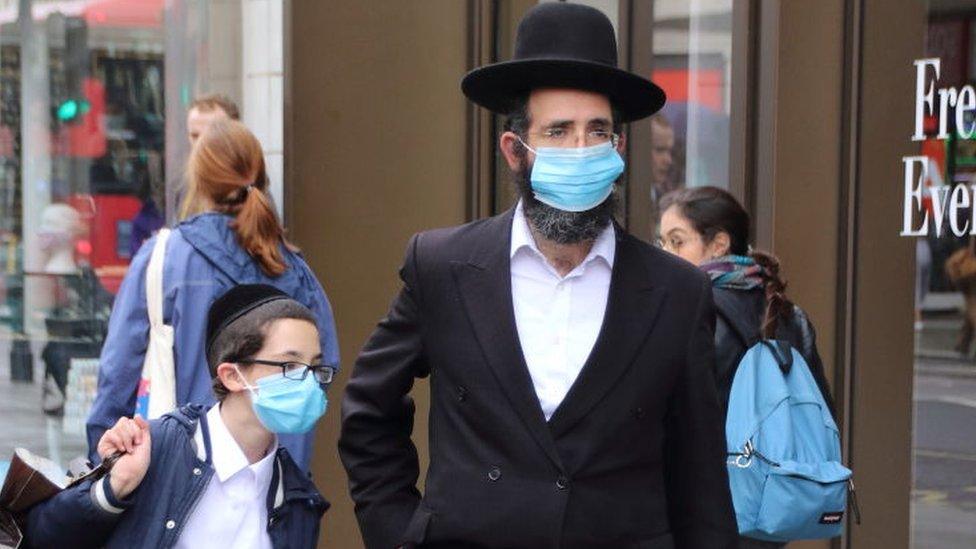 A Jewish man with his son walk along Oxford Street