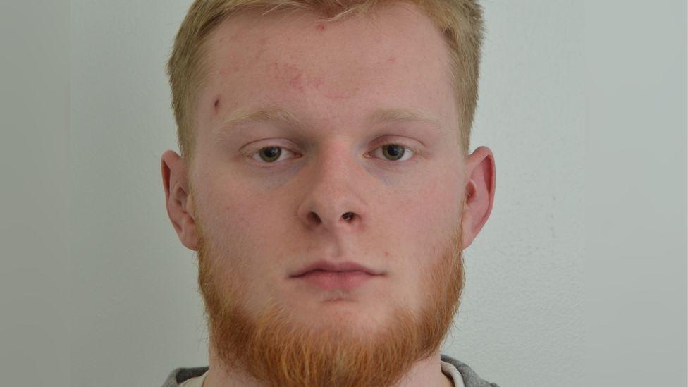Custody image of Jordan Richardson. He has short light-coloured hair and a ginger beard. He is looking directly at the camera.