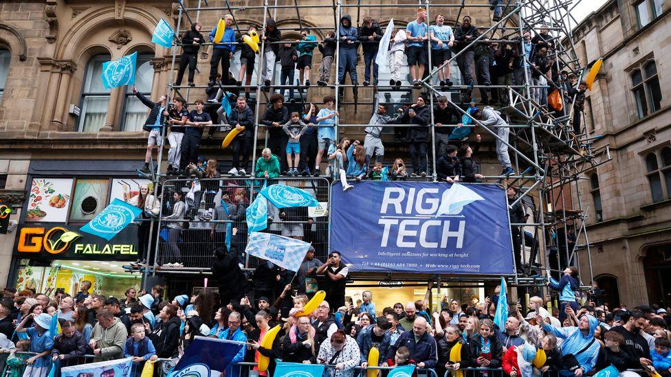 Fans on scaffolding outside a shop on Deansgate