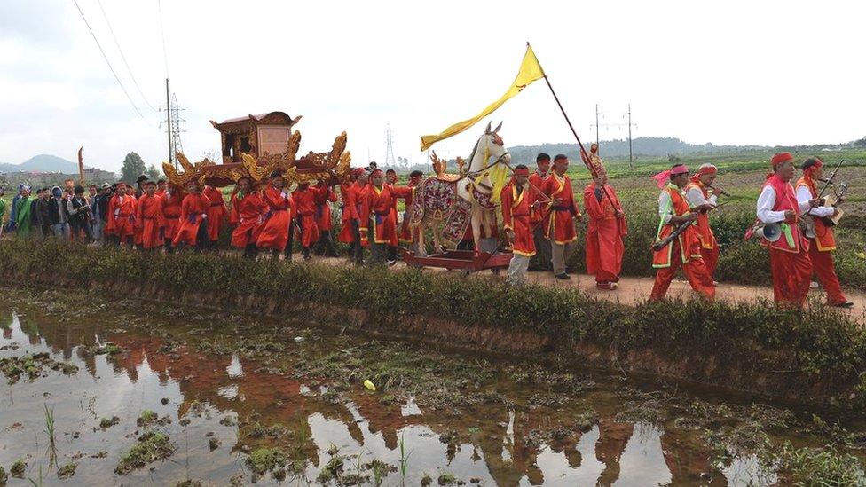 Villagers in festive costumes in a procession for the pig slaughter festival