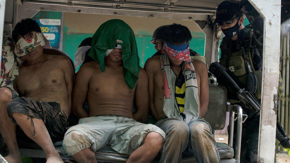 Suspected IS group members are transported in a police vehicle after being captured in a village in Marawi City on the southern island of Mindanao