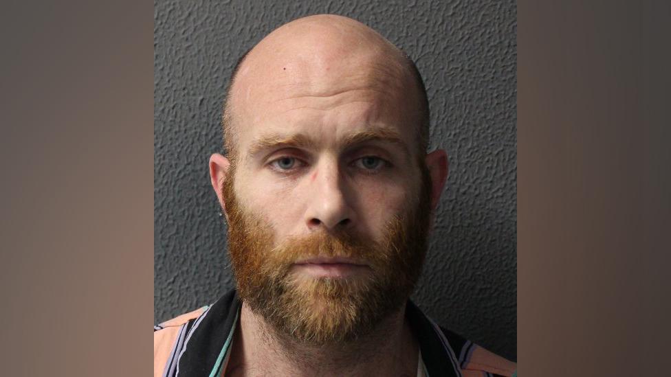 Police custody image of Nathan Arnold, a bald man with a ginger beard