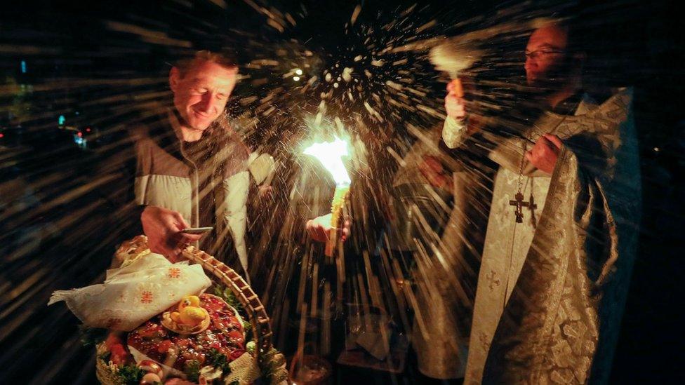 A Ukrainian priest (R) blesses believers waiting for the start of an Orthodox Easter Mass with baskets of painted eggs and kulichi, a traditional Easter cake, near St. Volodymir Cathedral in Kiev