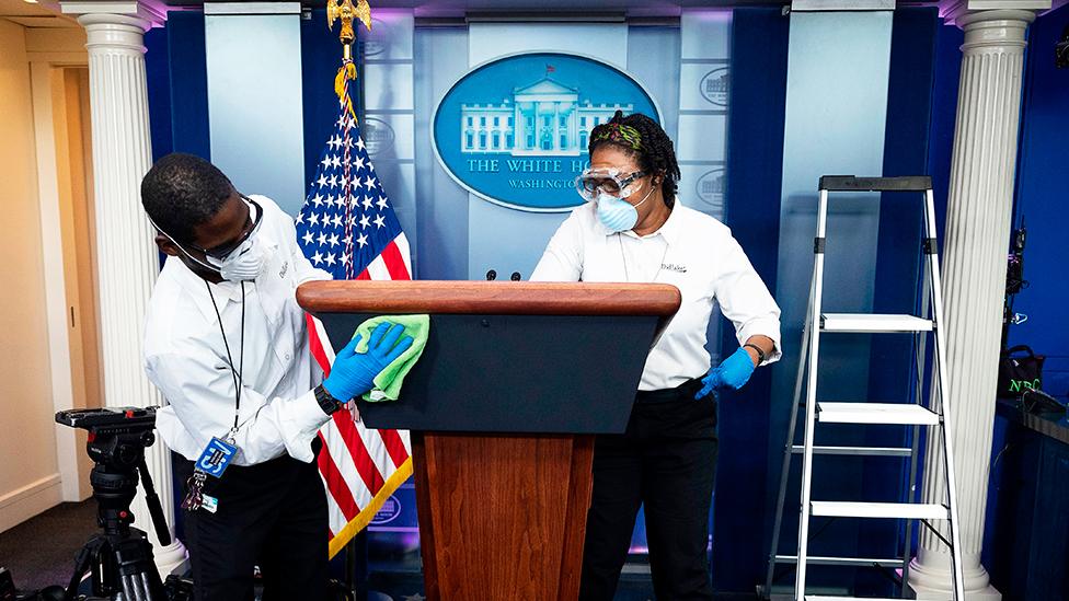 Cleaning staff disinfect the lectern in the White House Press Briefing Room - 9 April 2020