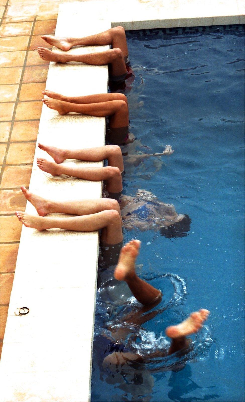 Children playing in the pool with their legs over the edge