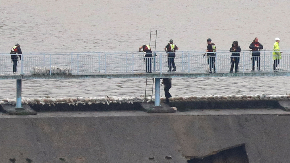 Workers put sandbags on reservoir edge