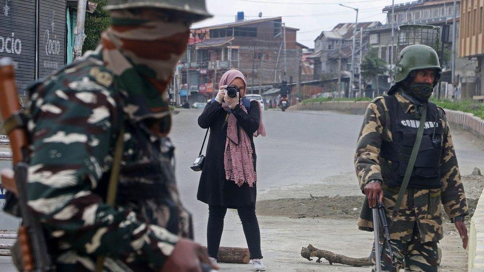 Photojournalist Masrat Zahra (Rear) takes photos near a temporary checkpoint before going to Cyber Police Station in Srinagar, Kashmir