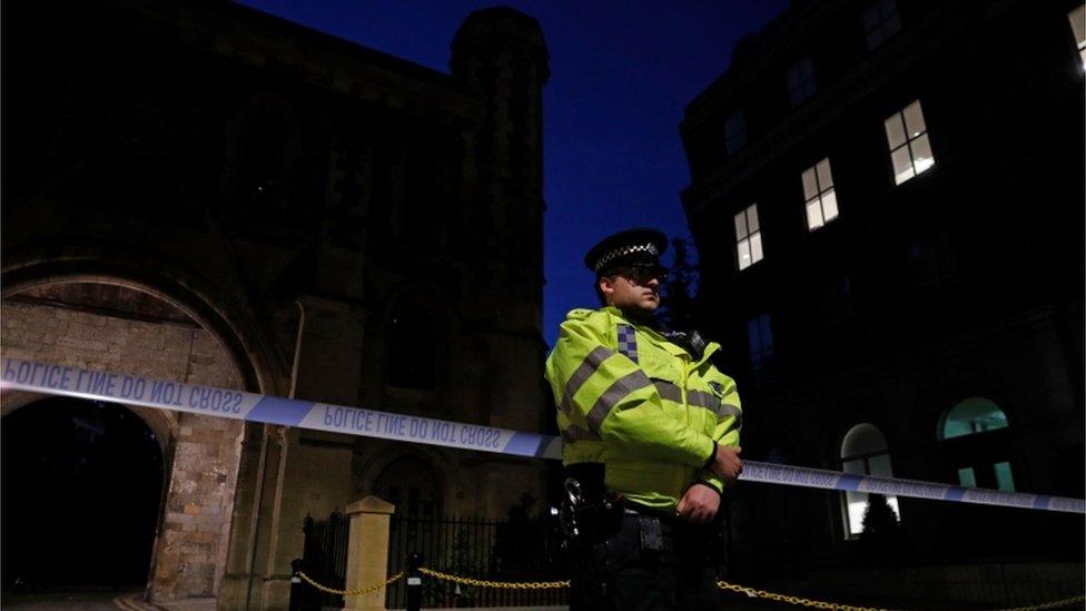 Police officer stands guard at the gatehouse entrance to the park