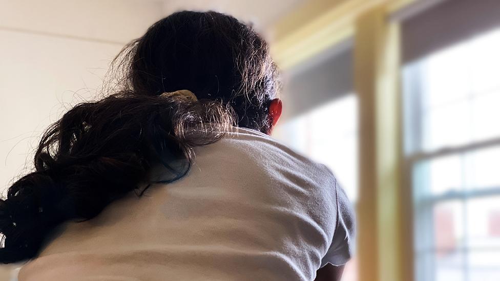 Picture shows the back of an anonymous young persons head and shoulders as they look out of a window