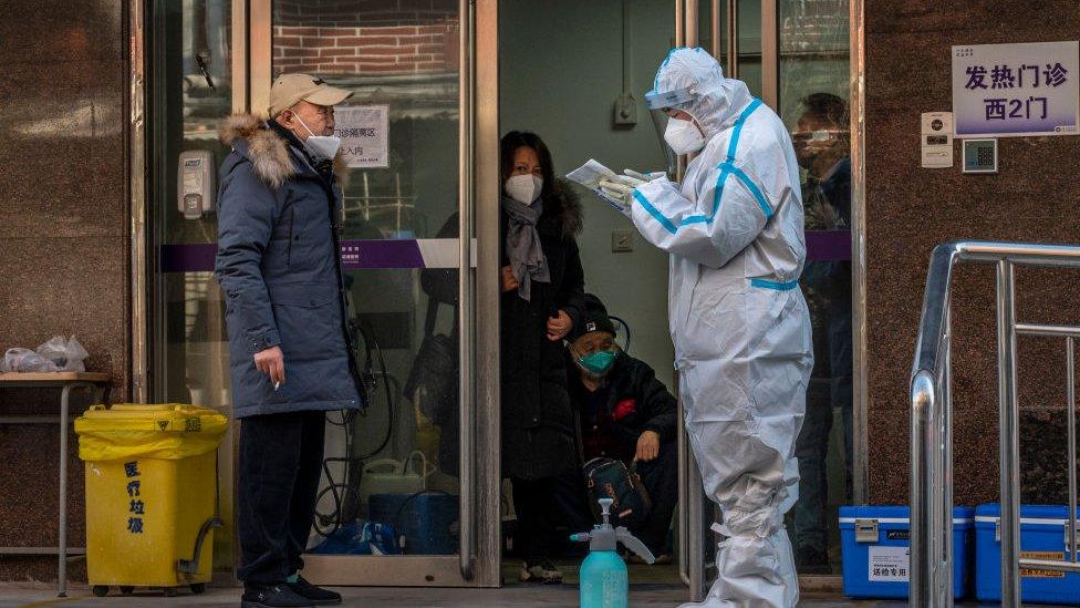 A medical worker wears PPE while he speaks to a patient at a covid clinic