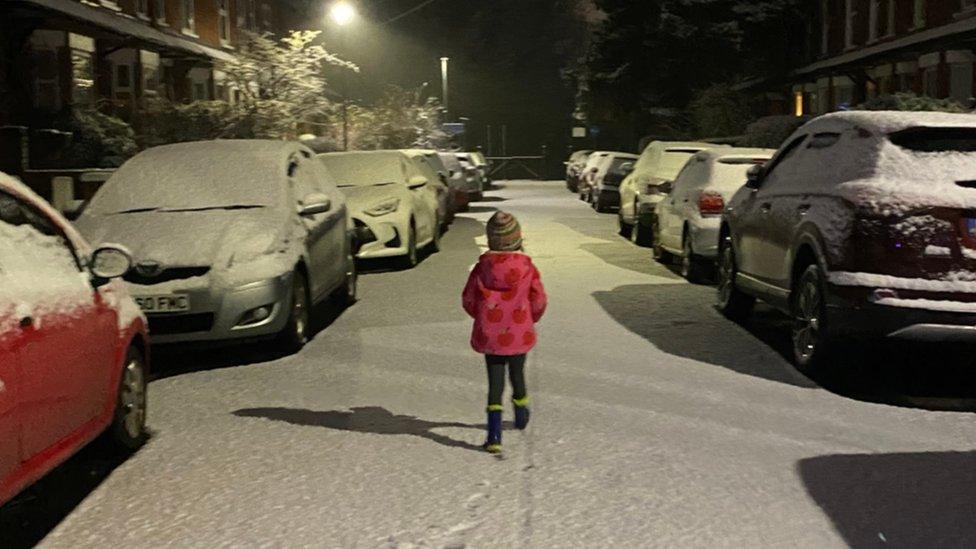 Child walks in fresh snow along street