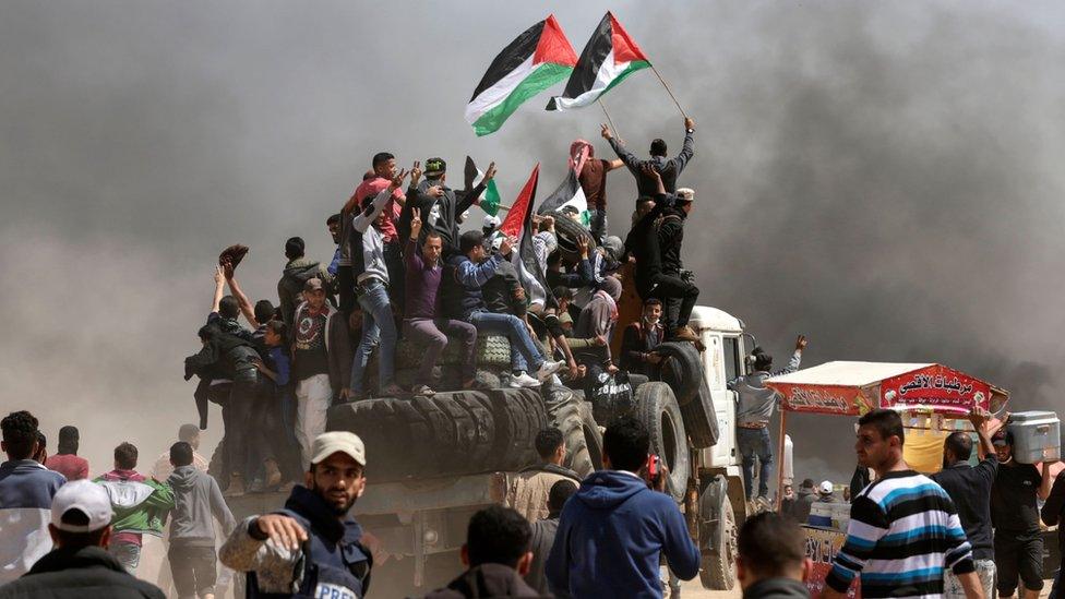 Palestinian men wave flags during a protest east of Gaza City on 6 April 2018