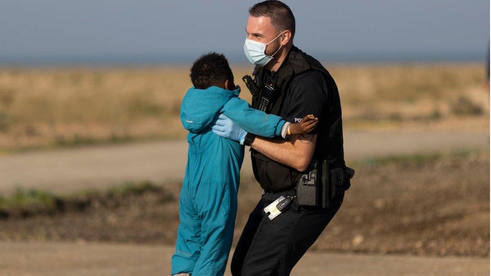 A border force official carries a migrant child after arriving on Dungeness beach on 7 September.