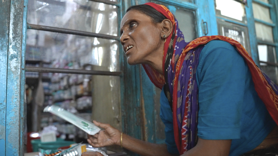 A woman collects a prescription.