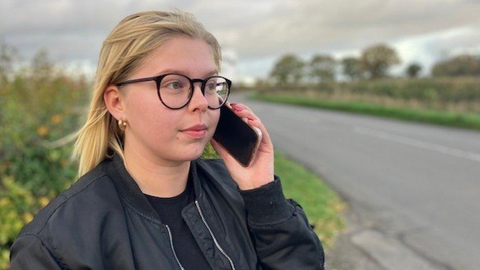 Woman holding mobile phone by roadside