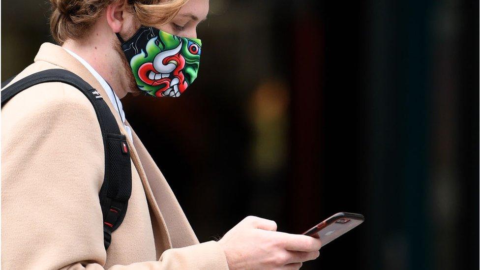 Woman looking at her phone and wearing a mask