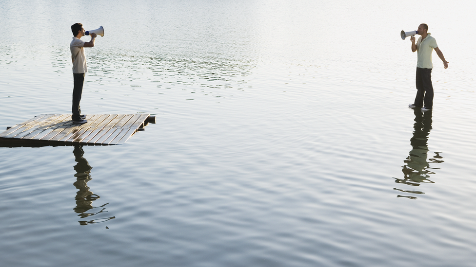 Two men standing on water with megaphones