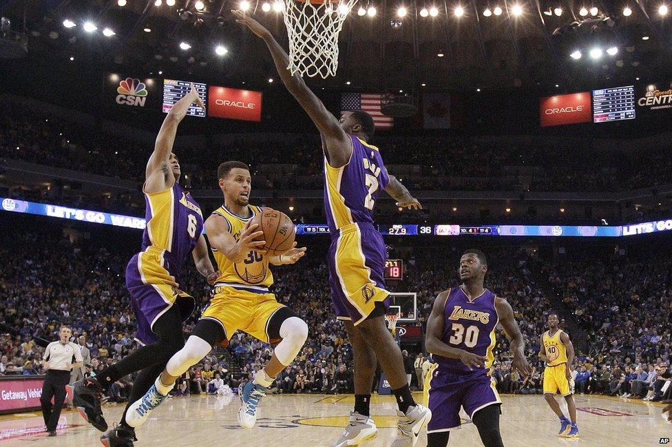 Golden State Warriors guard Stephen Curry, center, looks to pass as Los Angeles Lakers guard Jordan Clarkson