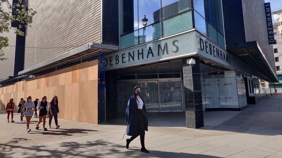 People walk by a closed Debenhams