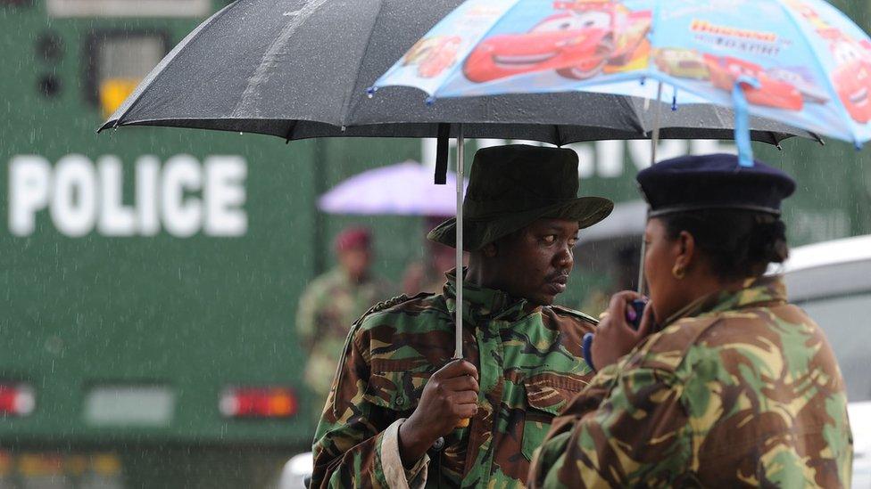 Kenyan police shield themselves from the rain November 14, 2017 outside the supreme court in Nairobi