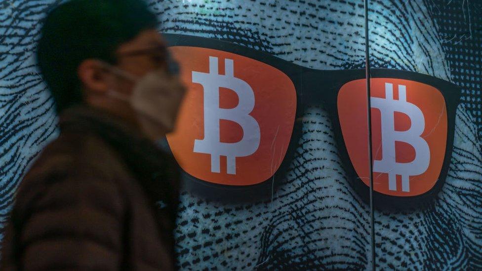 Pedestrians walk past a display of cryptocurrency Bitcoin on February 15, 2022 in Hong Kong, China.