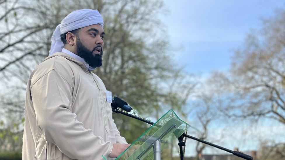 Masum Shaheed speaks into a microphone at an outdoor event