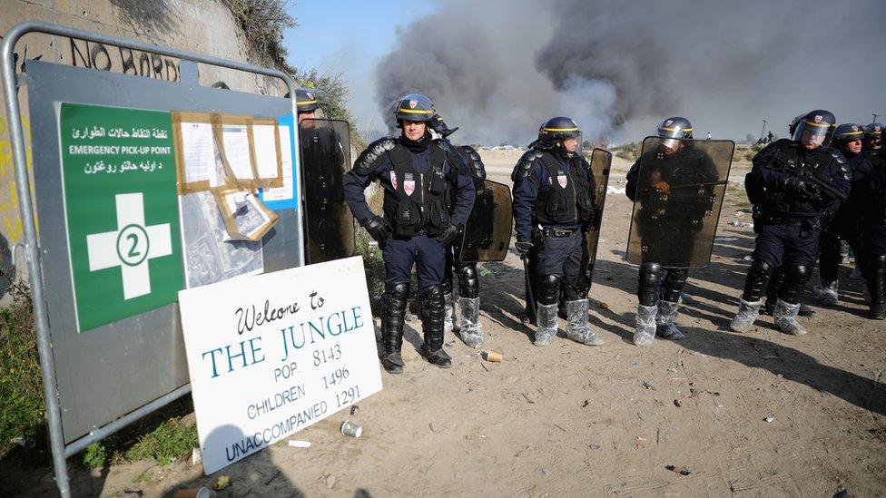 French police stand at the entrance of the migrant camp in Calais during the demolition.