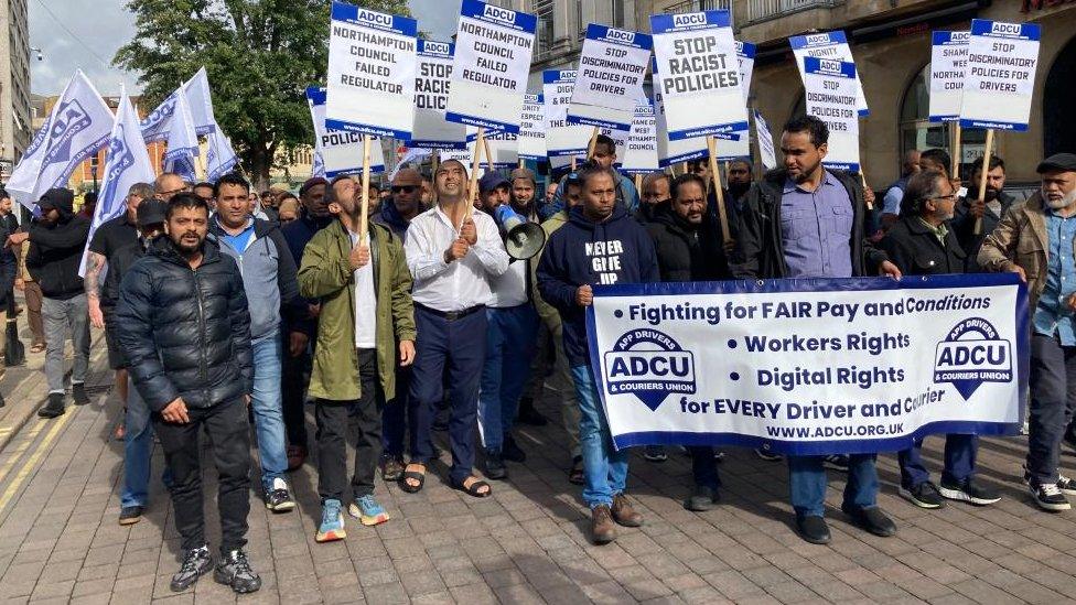 A group of men holding banners with various slogans including "stop racist policies"